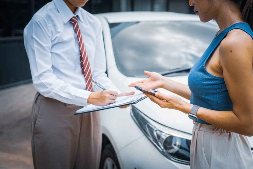 A young businesswoman reviews car insurance options at her desk, evaluating premiums, deductibles, coverage details, and managing claims efficiently.