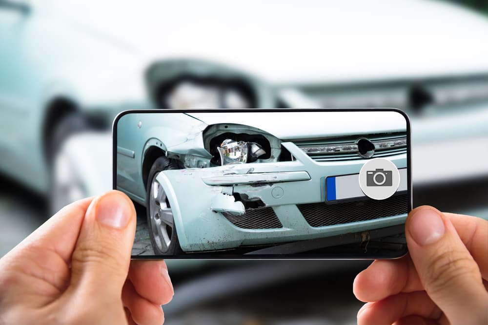 An agent takes pictures of damage to car after accident