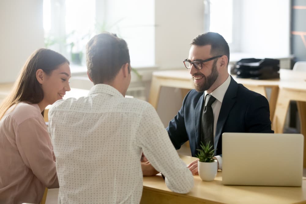 Professional attorney in suit providing legal guidance and advice to a young couple in a friendly consultation.