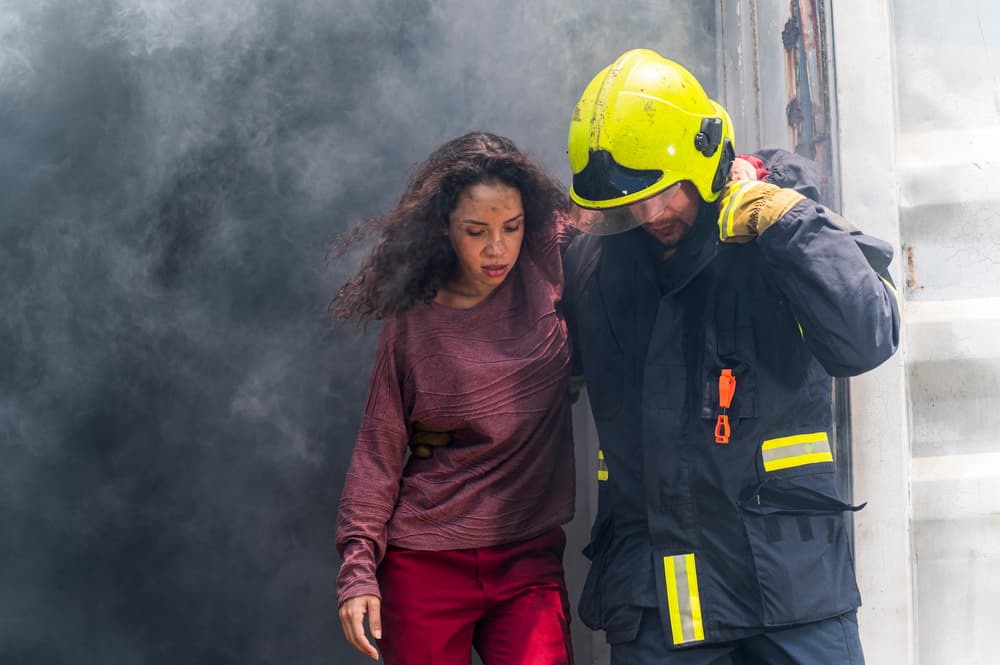 Bombero realizando un rescate de emergencia para ayudar a una mujer joven en medio de humo peligroso y un accidente en un edificio en llamas. - Ilustración del concepto de operación de seguridad y rescate.