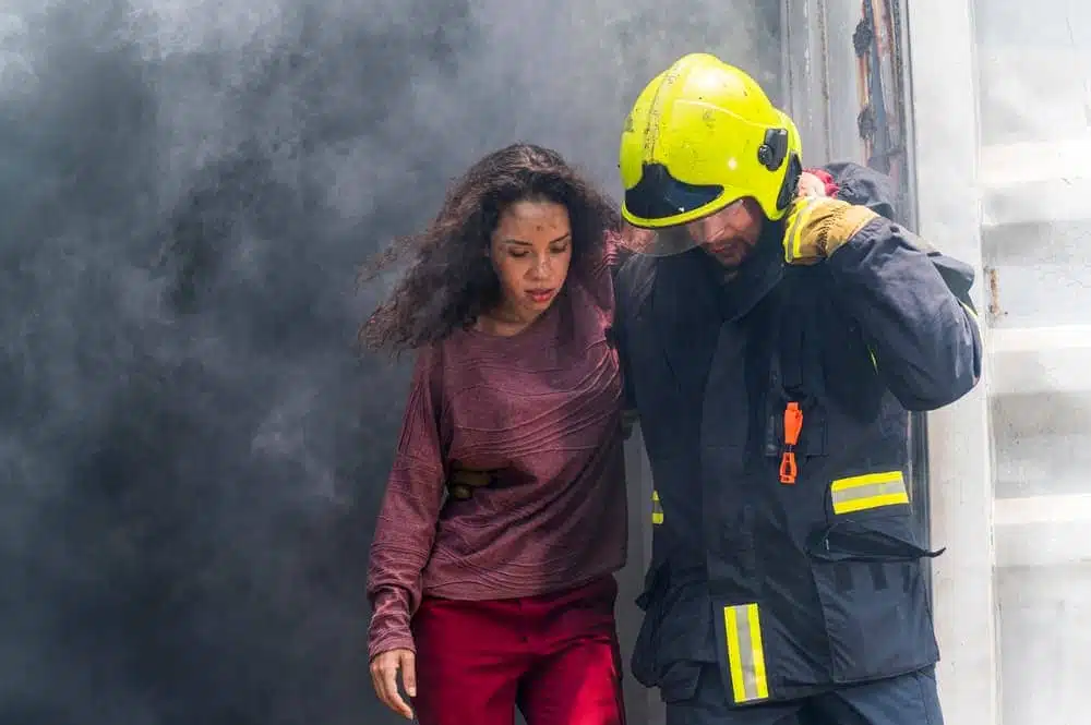 Firefighter conducting emergency rescue to aid a young woman amidst hazardous smoke and a burning building accident. - Illustration of safety and rescue operation concept.