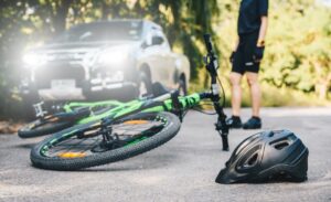 A fallen cycling helmet and bicycle on asphalt after a car accident on the road, illustrating a collision between a car and a bicycle.