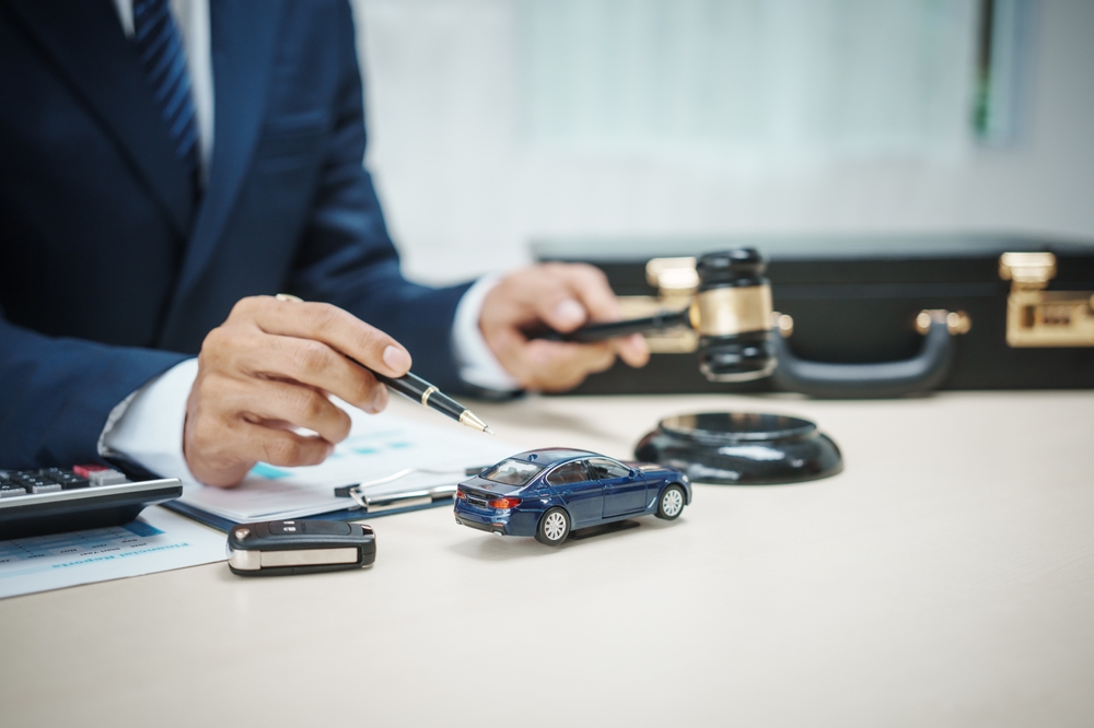 Un hombre trajeado vende coches en su despacho, ofrece seguros de coche en línea , préstamos para coches, cobertura a todo riesgo, retirada de efectivo mediante tarjetas de crédito