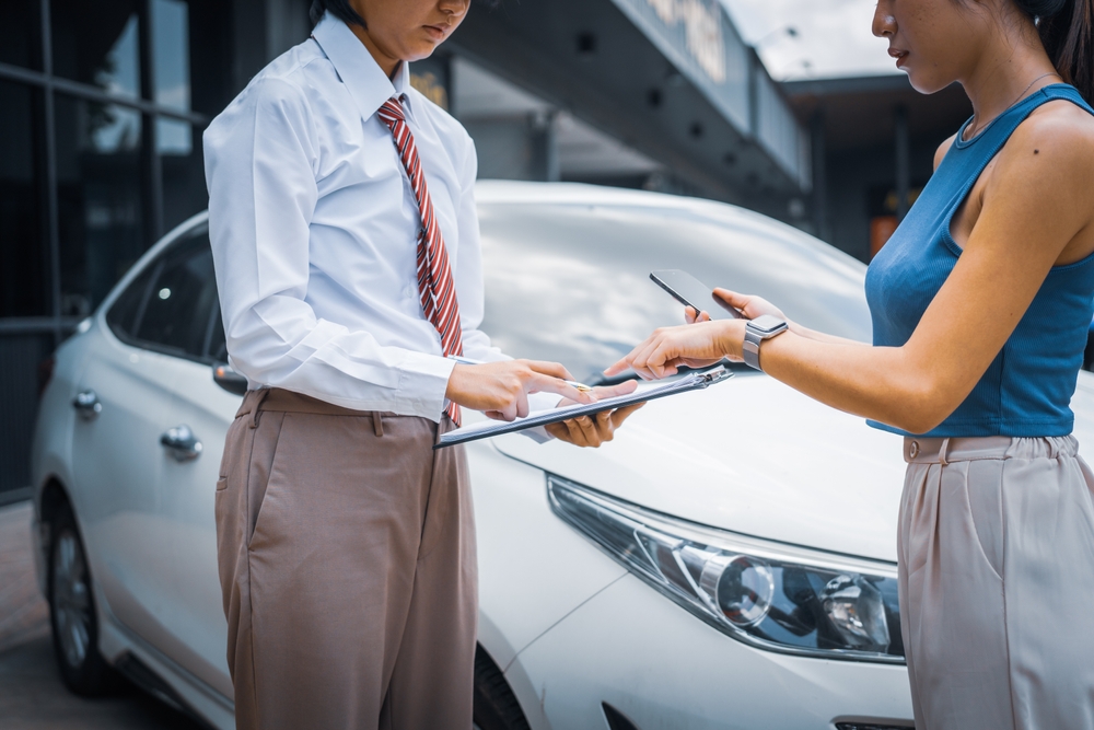 A young businesswoman is navigating car insurance options at her desk, considering premiums, deductibles, and coverage while understanding