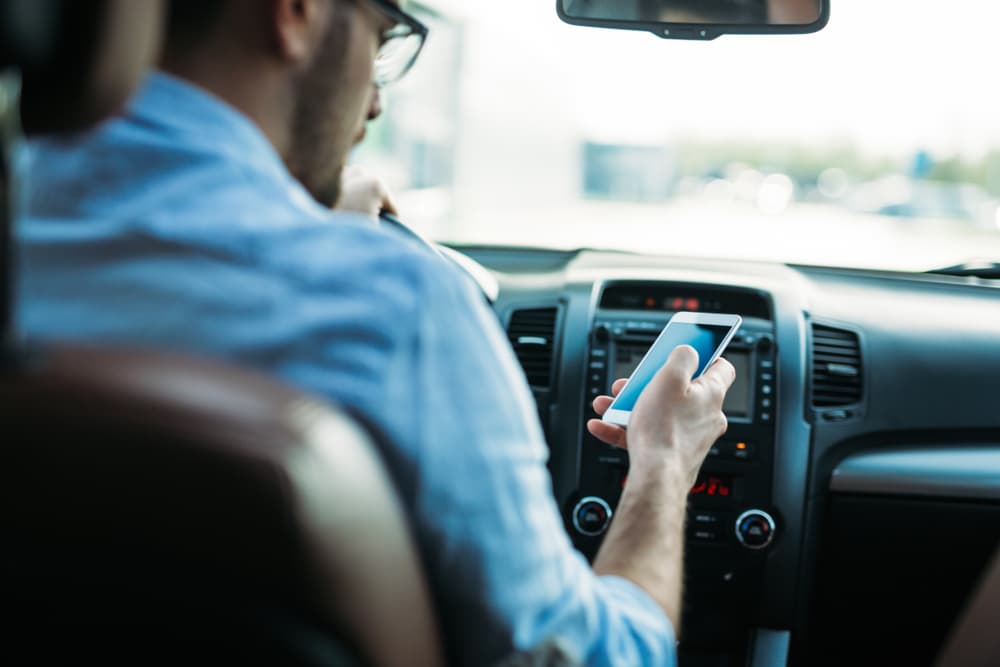 Businessman neglecting safety by texting on a mobile phone while driving