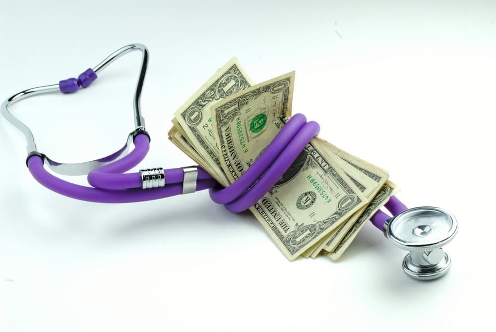 Medical stethoscope and a stack of dollar banknotes on a white background