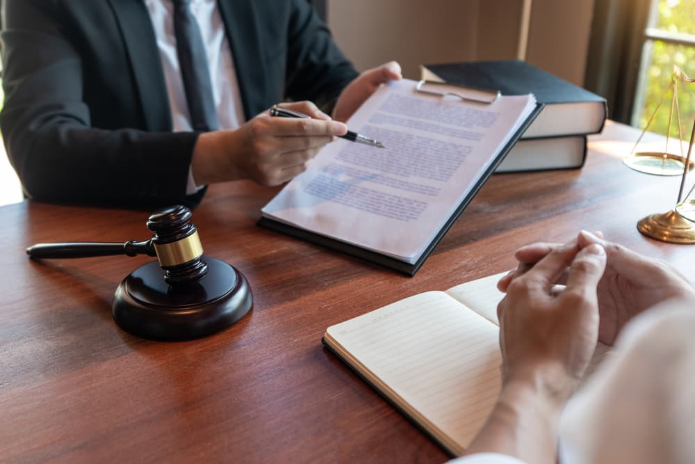 Male notary or lawyer discussing contract papers with a client in an office, representing legal services