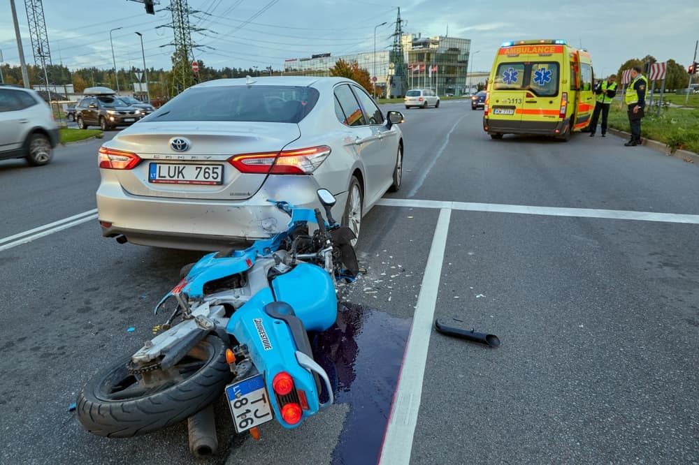 Damaged car and motorbike on city road after accident due to failure to maintain proper distance