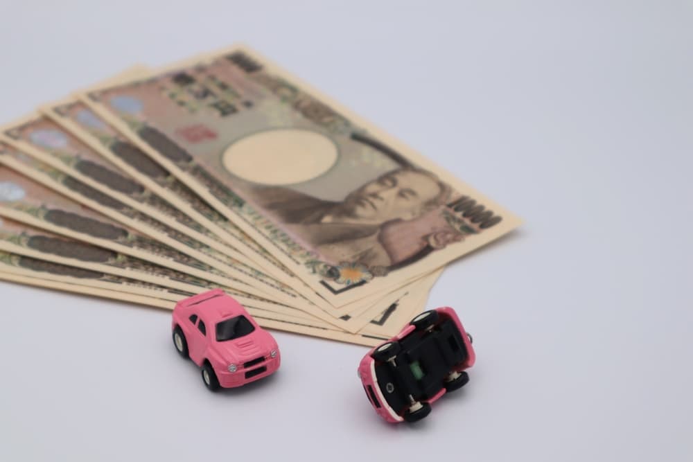 Toy cars next to banknotes, representing financial compensation after a car accident.