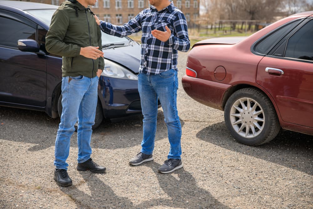 Two men having a heated discussion after a car accident on the road