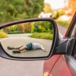 Reflection in rearview mirror showing a person struck by a car - illustrating a car accident concept