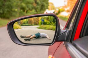 Reflection in rearview mirror showing a person struck by a car - illustrating a car accident concept